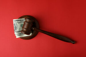 Judge gavel with dollars on red background